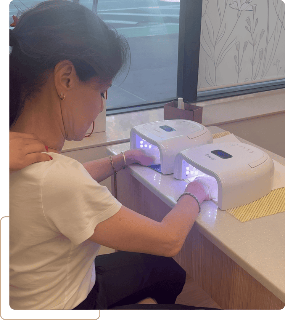 Woman curing nails under LED nail lamps